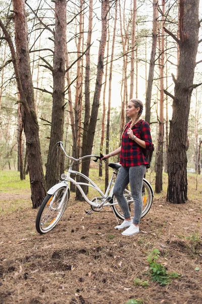 Beautiful young girl with a cruiser bicycle in the forest