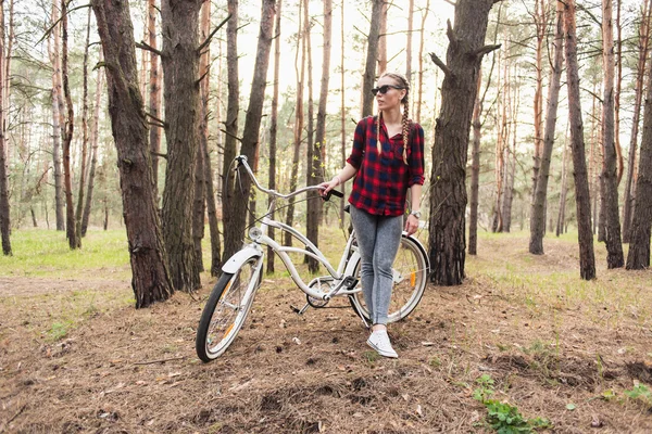 Beautiful young girl with a cruiser bicycle in the forest
