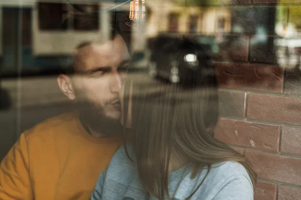 Couple in love kissing behind the window of cafe