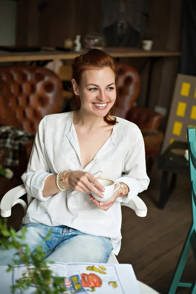Woman sitting and smiling with cup