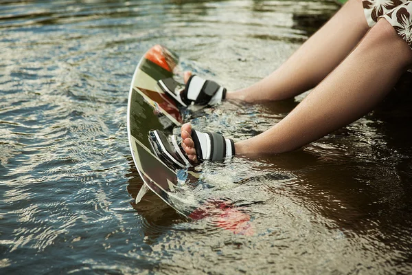 Men's feet on a wakeboard in water
