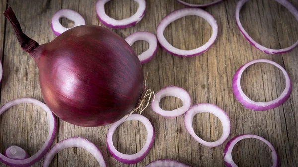 Red onions sliced on wooden background