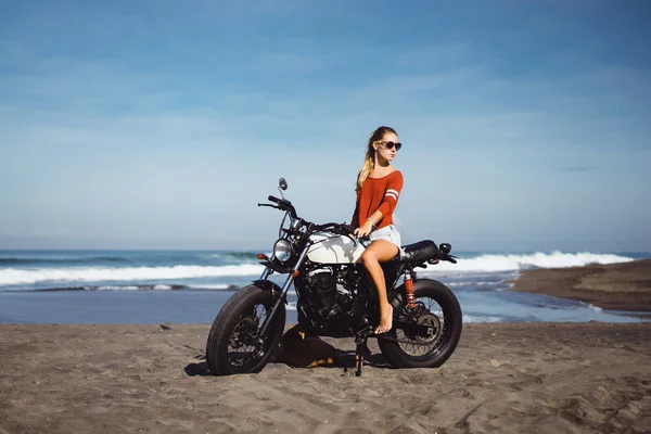 Woman sitting on vintage custom motorcycle
