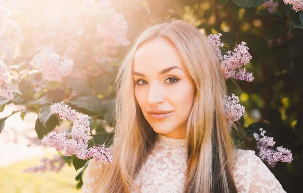 Blonde girl posing near flowers