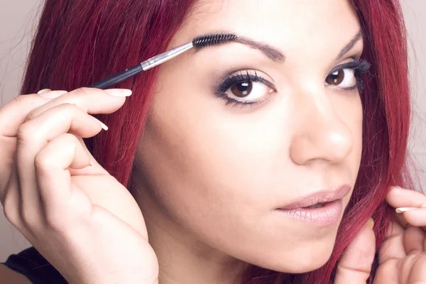 Portrait of a redhead beauty with a eyebrow brush tool