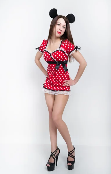 Beautiful young leggy brunette in a very short red dress with white polka dots on the legs black high-heeled shoes. full height