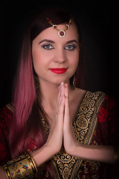 Closeup of Beautiful caucasian woman dressed in oriental style with oriental patterns on the hands and face, with numerous bracelets. Indian woman doing namaste hands sign