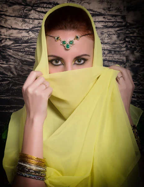 Closeup of beautiful young woman with oriental make-up and shawl over her head. caucasian woman dressed in oriental style