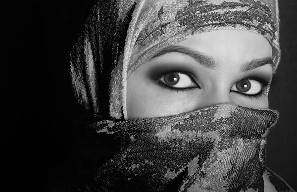 Close-up beautiful mysterious eyes eastern woman wearing a hijab. black and white