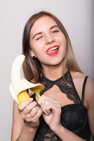 Young amazed woman in lacy lingerie holding a banana, she is going to eat a banana