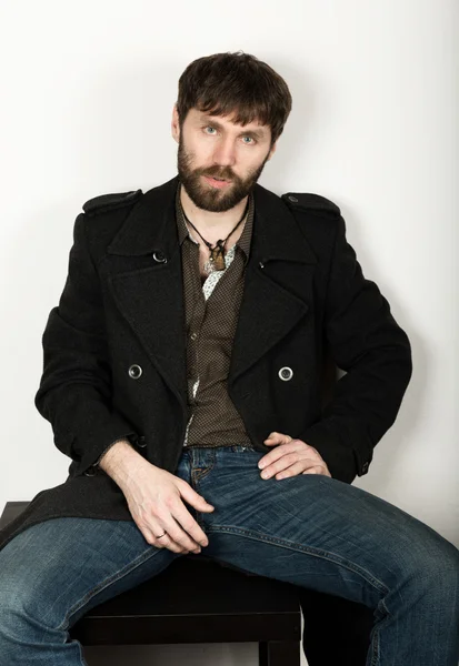 Handsome bearded elegant business man in a jacket, jeans and a woolen coat posing. feshion concept