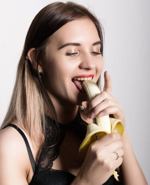 Young amazed woman in lacy lingerie holding a banana, she is going to eat a banana. she sucks a banana