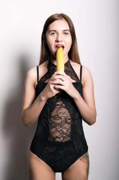 Young amazed woman in lacy lingerie holding a banana, she is going to eat a banana