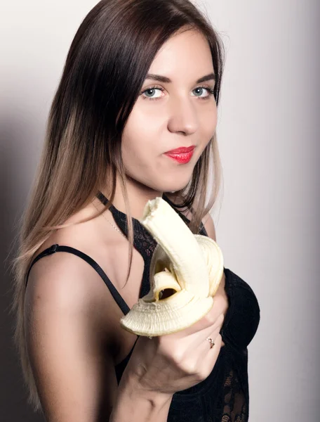 Young amazed woman in lacy lingerie holding a banana, she is going to eat a banana. woman offers to eat banana