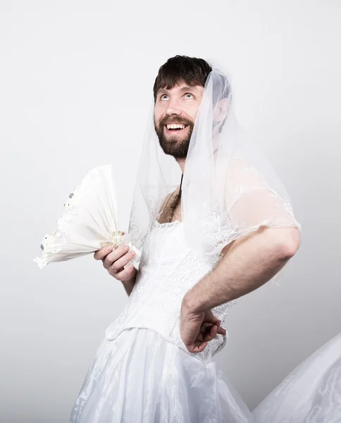 Bearded man in a womans wedding dress on her naked body, holding a flower. on his head a veil. funny bearded bride, different emotions