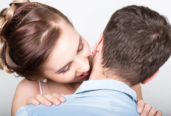 Closeup of a young couple in love, man stands with his back to the camera, she gently touches  tongue to his neck. Playful couple.