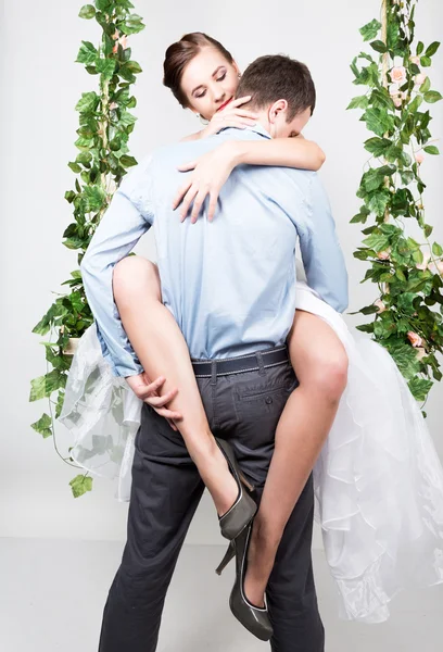 Closeup of a young couple in love, man stands with his back to the camera, she bites his ear. Playful couple. her legs hugging man