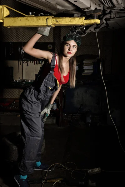 Beautiful young female mechanic inspecting car in auto repair shop. Sexy mechanic