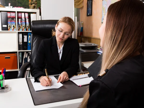 Attractive business woman working with documents in office. woman in a business suit sitting at a table and sign documents