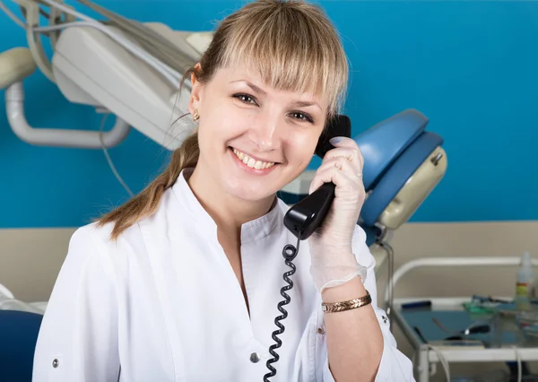 Administrator at the dental clinic holding the phone, records of patients on reception