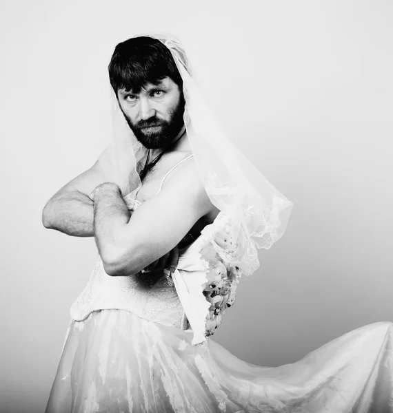 Bearded man in a womans wedding dress on her naked body, holding a flower. funny bearded bride, black and white