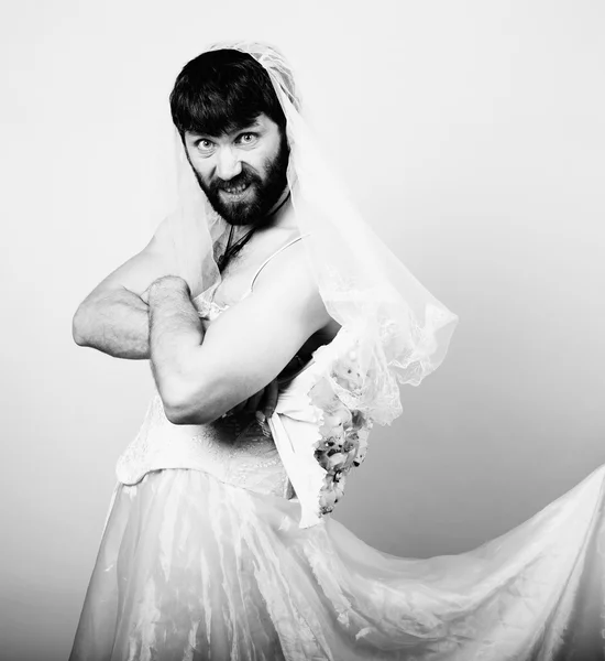 Bearded man in a womans wedding dress on her naked body, holding a flower. funny bearded bride, black and white