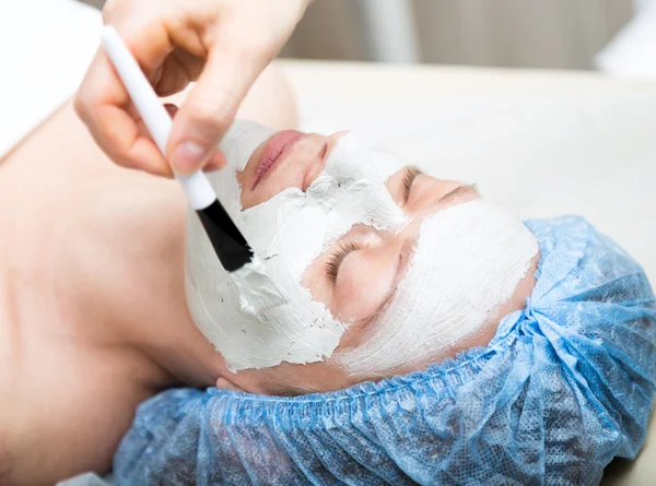Young woman lying down in a spa salon and having a facial beauty treatment. The cosmetic procedures for the face. Beauty treatments in the spa salon. Facial Skin Care