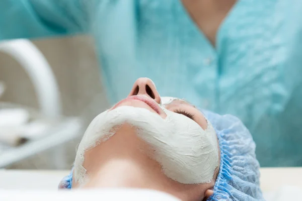 Young woman lying down in a spa salon and having a facial beauty treatment. The cosmetic procedures for the face. Beauty treatments in the spa salon. Facial Skin Care