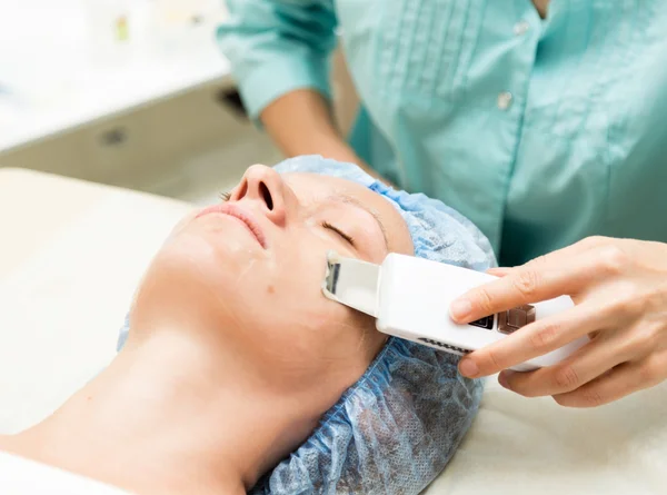 Young woman lying down in a spa salon and having a Ultrasonic face cleaning. The cosmetic procedures for the face. Beauty treatments in the spa salon. Facial Skin Care