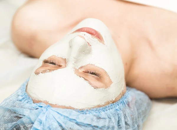 Young woman lying down in a spa salon and having facial beauty treatment. The cosmetic procedures for the face. Skin Care