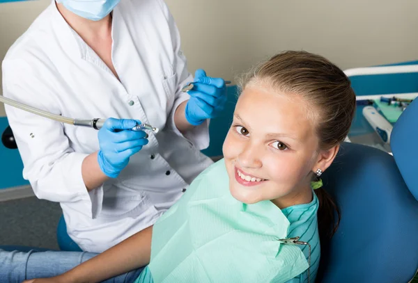 Happy little girl with open mouth undergoing dental treatment at clinic. Dentist checked and curing teeth a child patient in the dental office