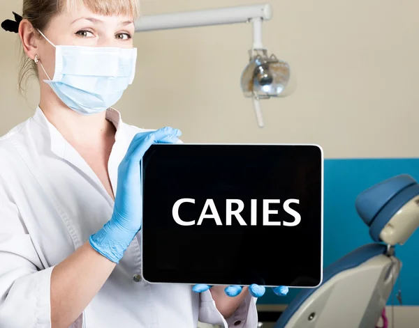Technology, internet and networking in medicine concept - femail dentist holding a tablet pc with caries sign. at the dental equipment background