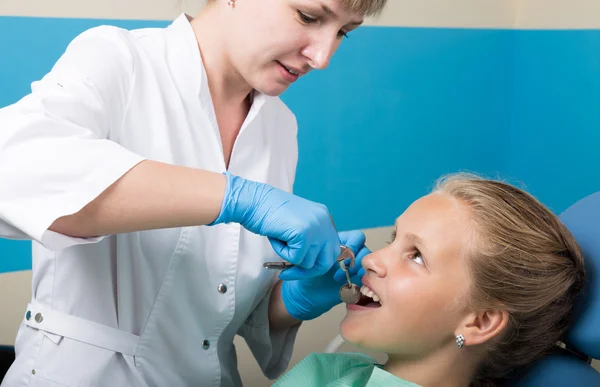 Happy little girl with open mouth undergoing dental treatment at clinic. Dentist checked and curing teeth a child patient in the dental office