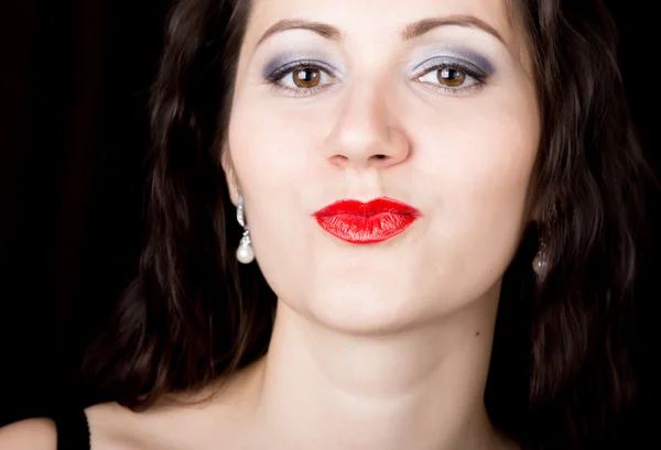 Close-up woman looks straight into the camera on a black background. expresses different emotions, sending a kiss