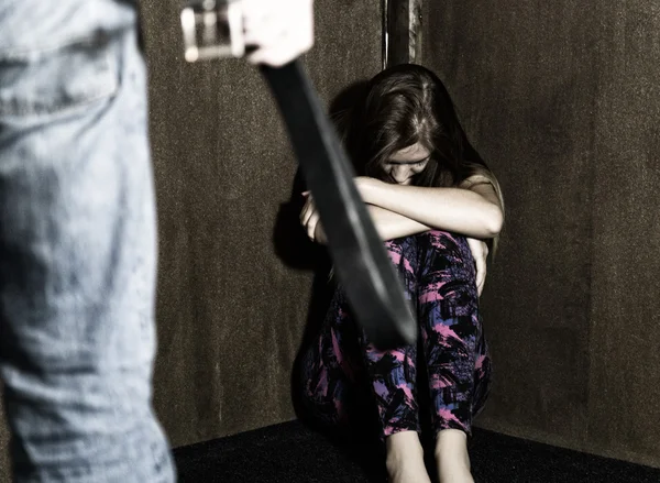 Frightened woman sitting in the corner with a faceless man holding a belt, a conceptual shoot portraying the process and effects of domestic violence