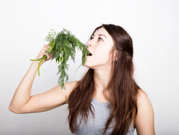 Beautiful young woman eating an vegetables. holding dill and parsley. healthy food - healthy body concept