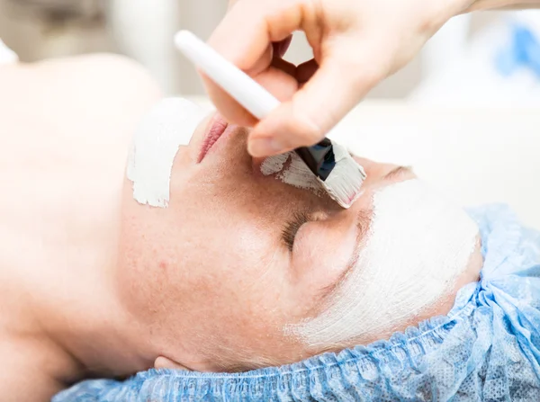 Young woman lying down in a spa salon and having a facial beauty treatment. The cosmetic procedures for the face. Beauty treatments in the spa salon. Facial Skin Care