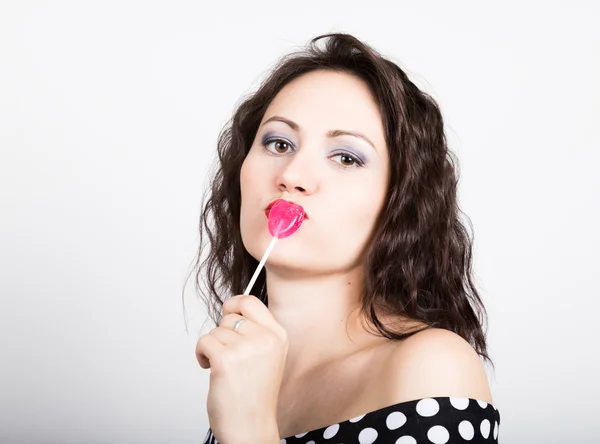 Portrait of happy beautiful young woman licking sweet candy and expressing different emotions. pretty woman with heart shaped lollipop