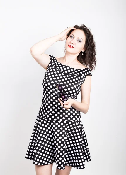 Beautiful young woman removes sun glasses, wears a dress with polka dots. expressing different emotions