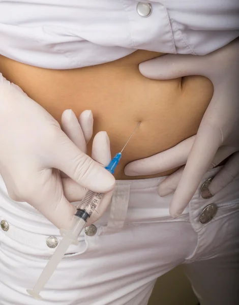 Closeup of a slim girls hands as she gives herself a shot. She holding a syringe