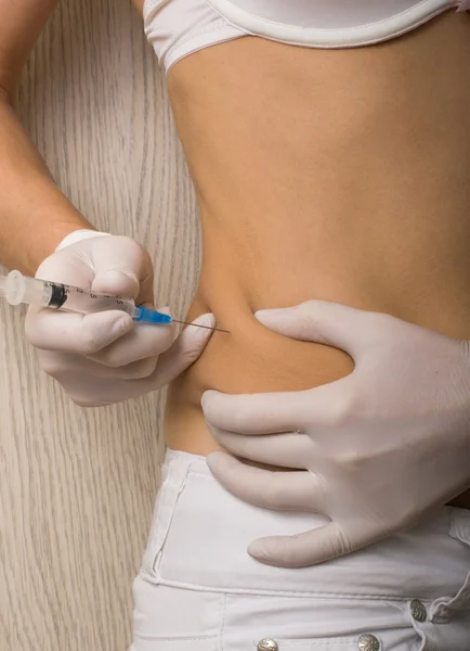 Closeup of a slim girls hands as she gives herself a shot. She holding a syringe