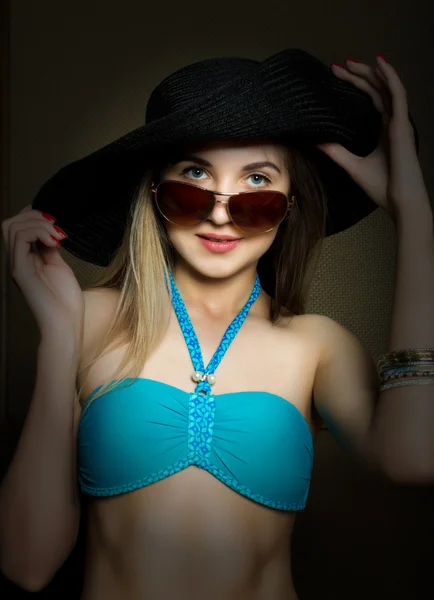 Beautiful young lady in a bathing suit, big black hat on high heels, and sunglasses