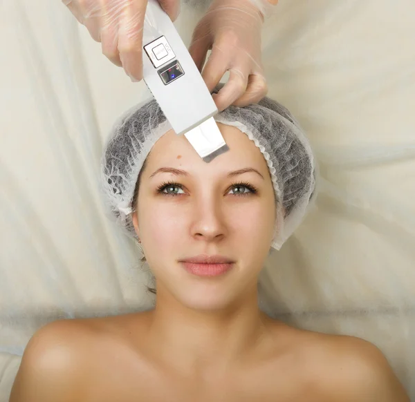 Beautician examining the face of a young female client at spa salon. ultrasonic cleaning person. Professional consultation