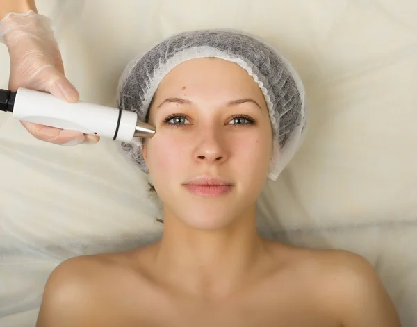 Beautician examining the face of a young female client at spa salon. getting rf-lifting in a beauty salon. Professional consultation