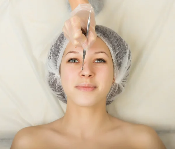 Beautician examining the face of a young female client at spa salon. face cleaning, Una cuchara. Professional consultation