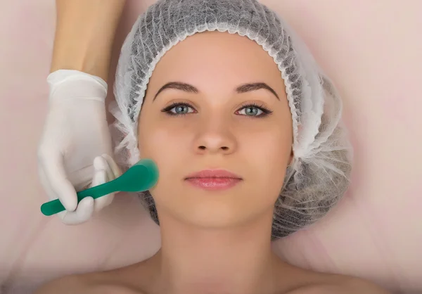 Beautician examining the face of a young female client at spa salon. beautician does cosmetic mask on the patients face. Professional consultation