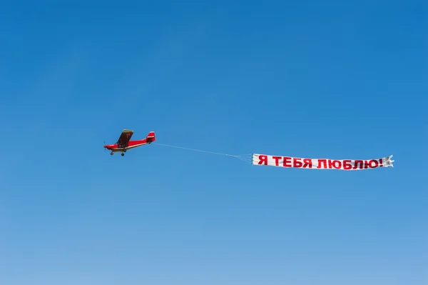 Red propeller plane in a blue sky with banner I love you