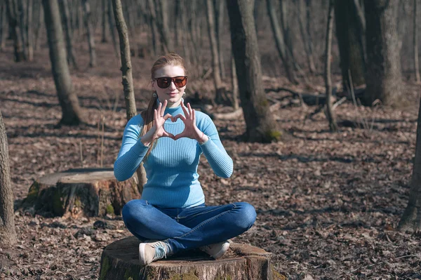 Beautiful girl blonde sits in lotus pose in the middle of the forest in the spring