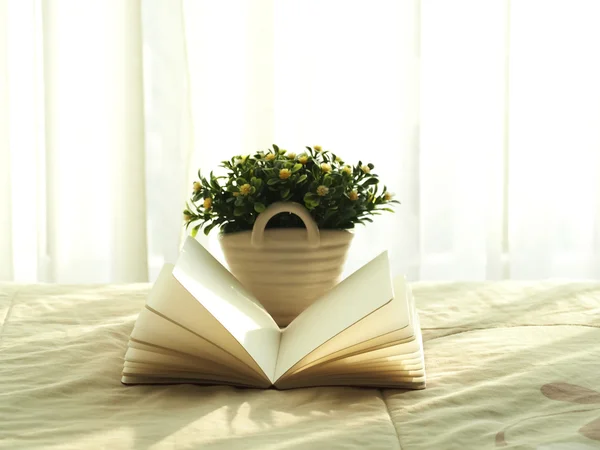 Fresh morning book and flower on the bed, select focus.