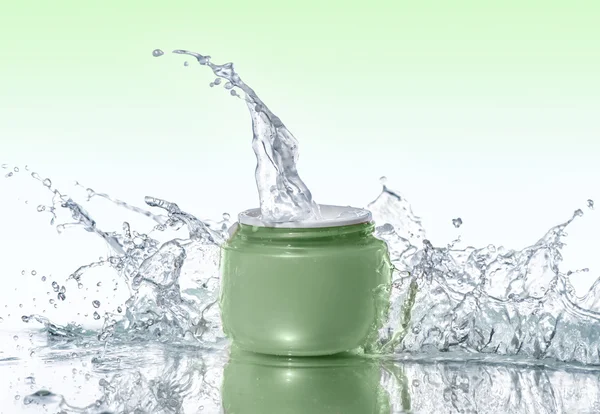 Green jar of moisturizing cream stays on the water background with  water splashes around